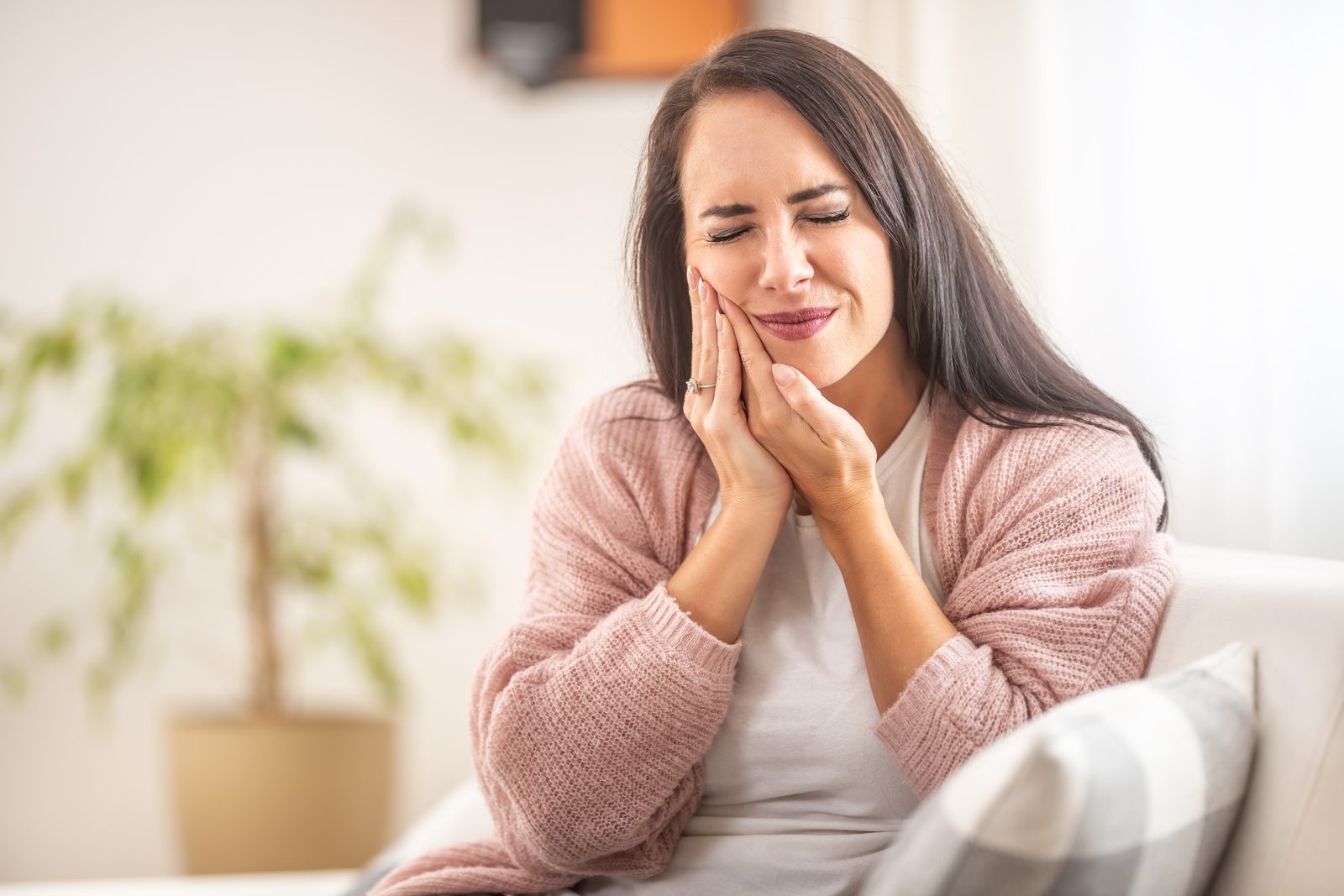 Woman with sudden tooth pain holding her jaw