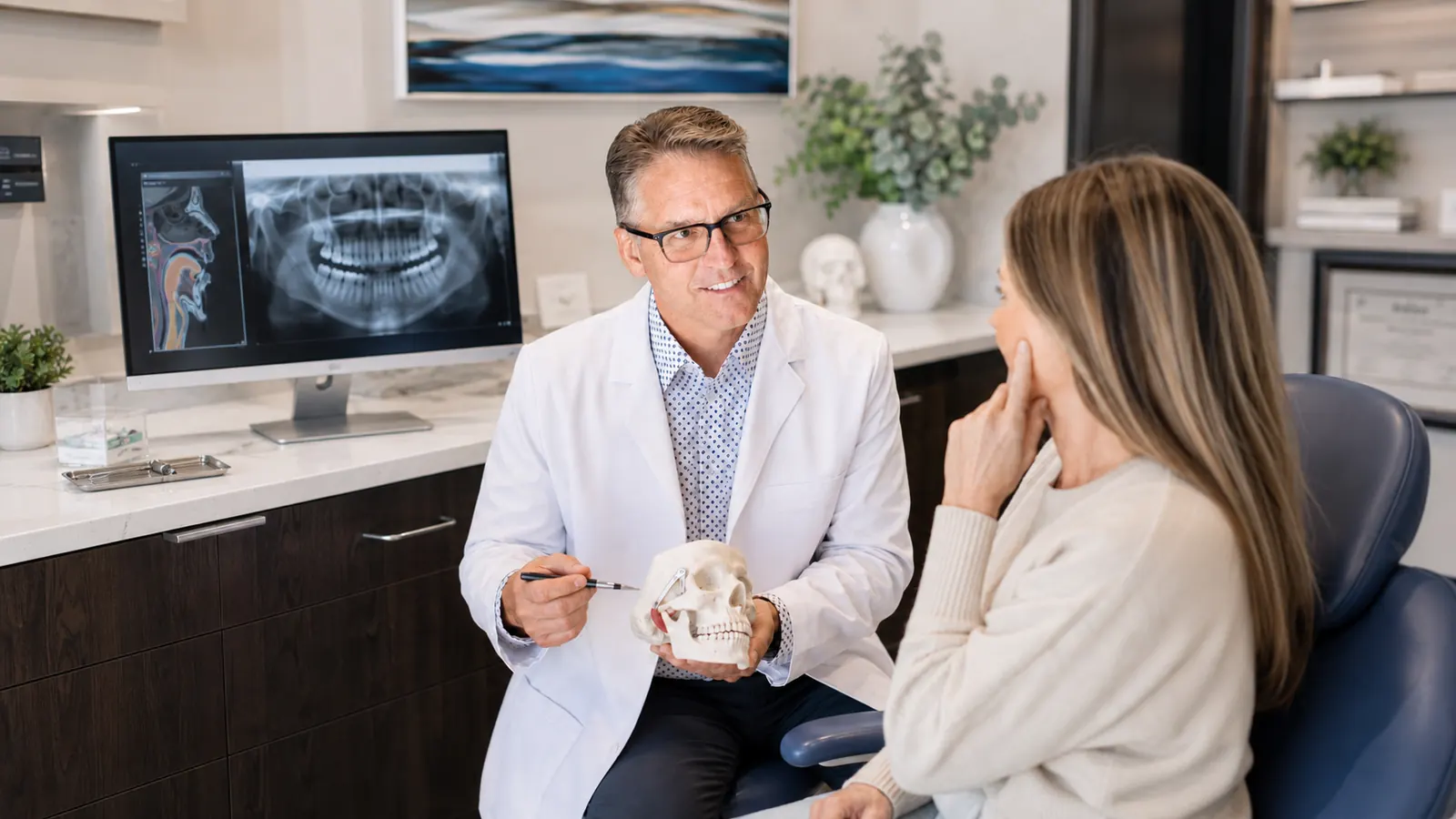 Dr. Mike Bennett showing a patient the temporomandibular joint on a skull model, TMJ consultation at Advanced Dental Care in Provo, Utah